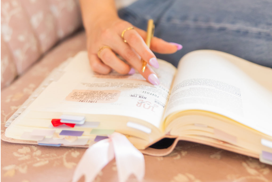 Person reading the bible with a pen and highlighter, sitting on a couch.