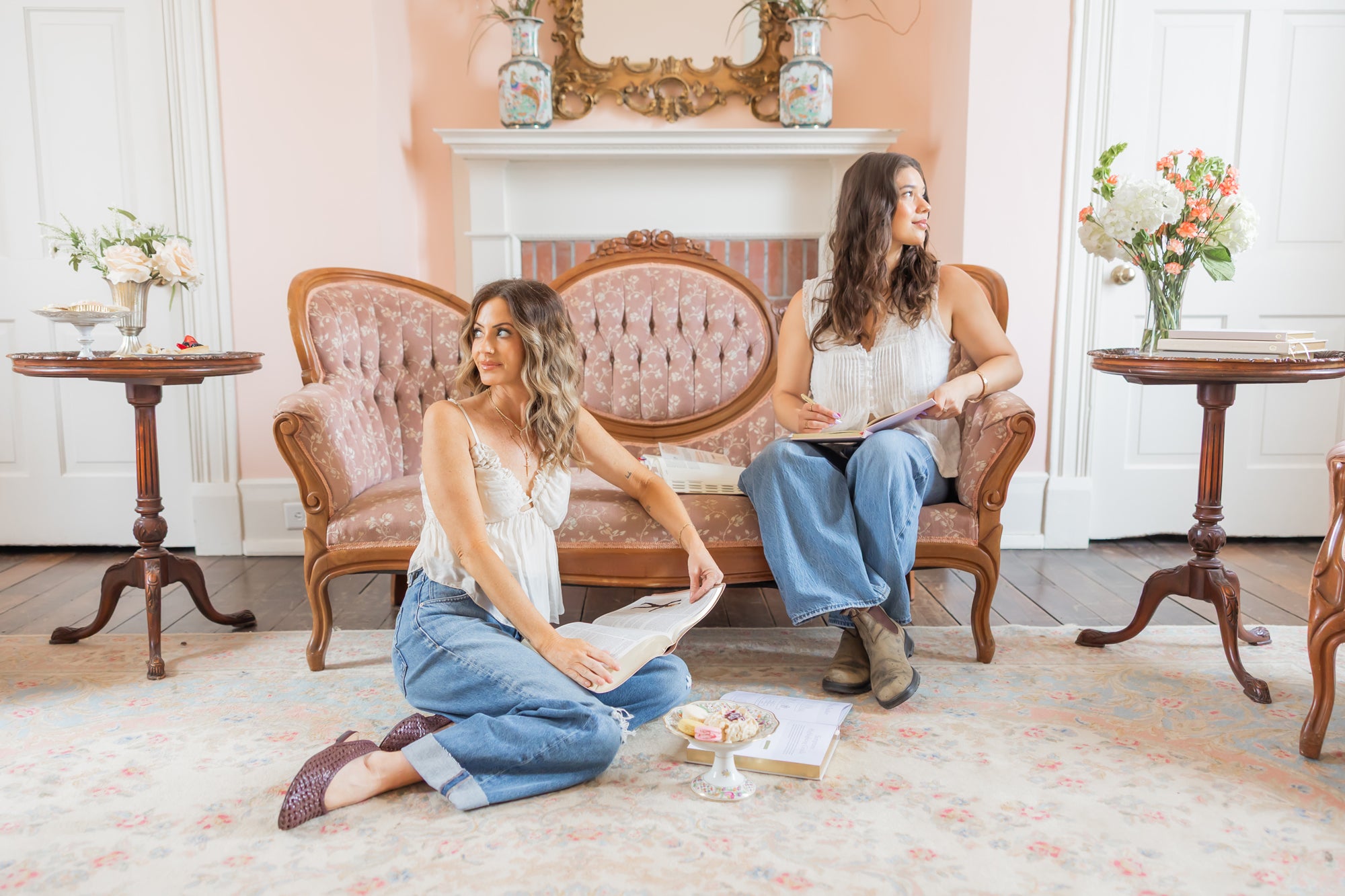 Two women sitting on a vintage couch in a romantic room with bibles and bible accessories.